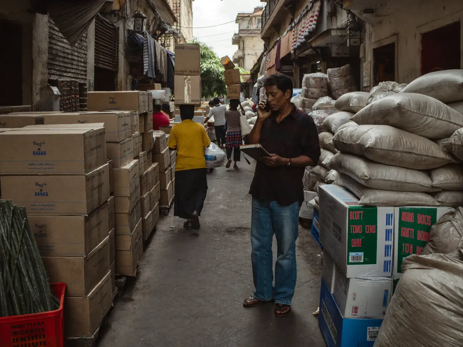 Wholesaler on the phone among stacked cartons in a wholesale market